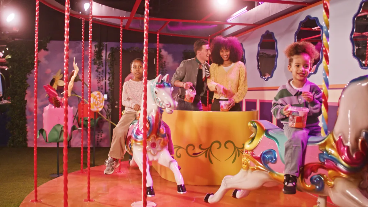 Visitors enjoying a colorful carousel ride at iCandy NYC